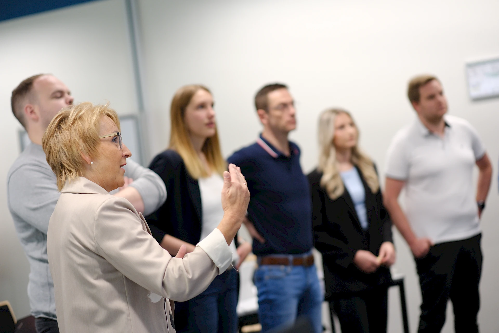Eine Dozentin erklärt einer Gruppe von Teilnehmenden Inhalte an Flipcharts