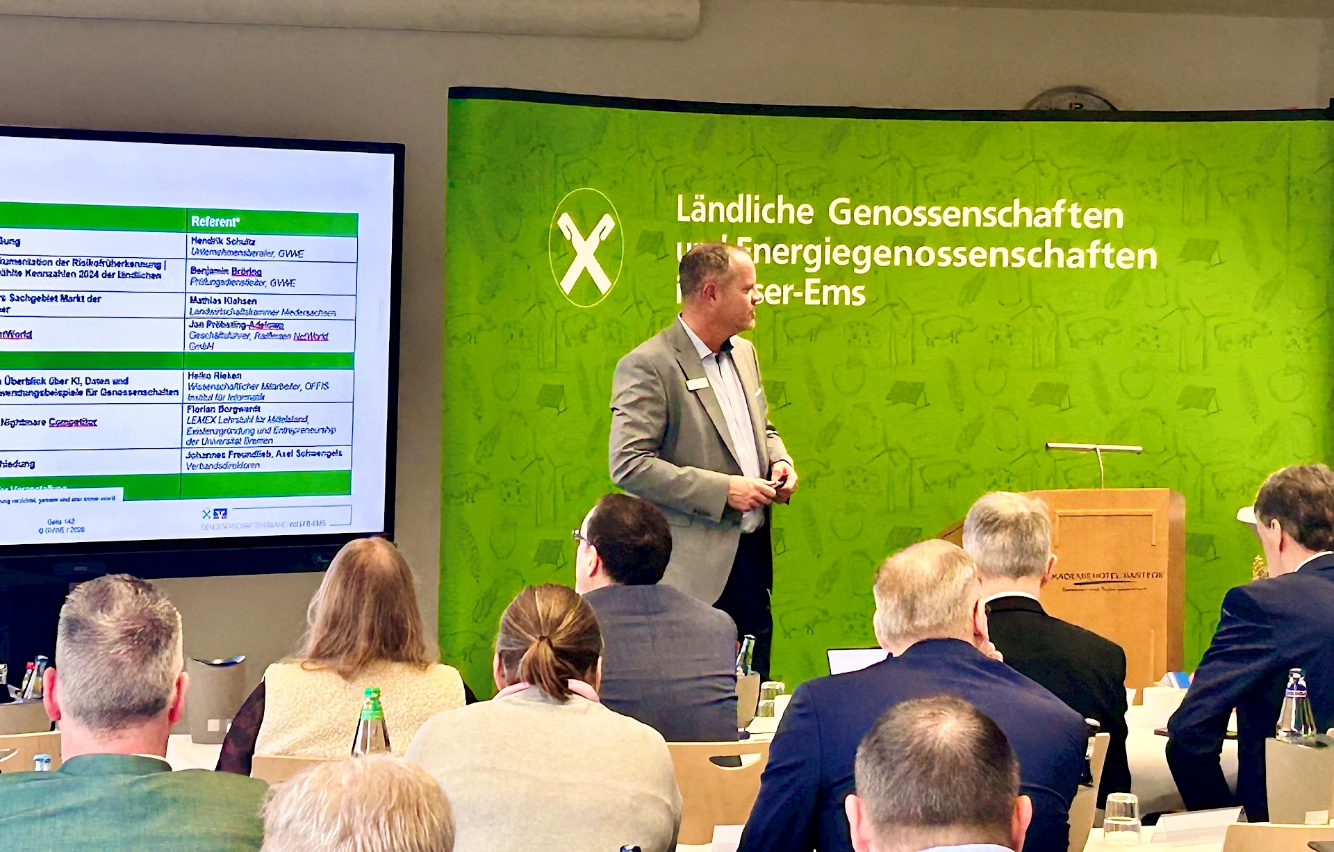 Moderator vor sitzenden Tagungsteilnehmern.